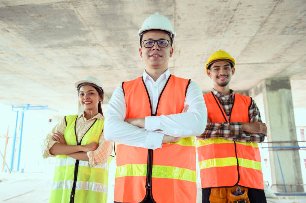 istock Indoor group portrait of professional look young Asian engineer or architect and construction worker at under construction site building. 1430100886