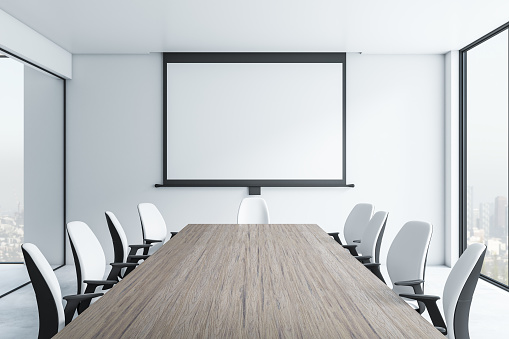 Front view on blank white poster in black frame on light wall in modern meeting room with empty wooden table surrounded by black and white chairs and city view from big window. 3D rendering, mock up