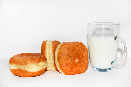 Delicious sweet buns with jam and a glass of milk on a white background. A delicious breakfast of beautifully fried buns and milk. White isolated background.