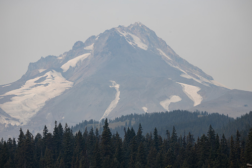 Snow on the peak of Mount Hood in northern Oregon on a late summer day with wildfire smoke in the sky.