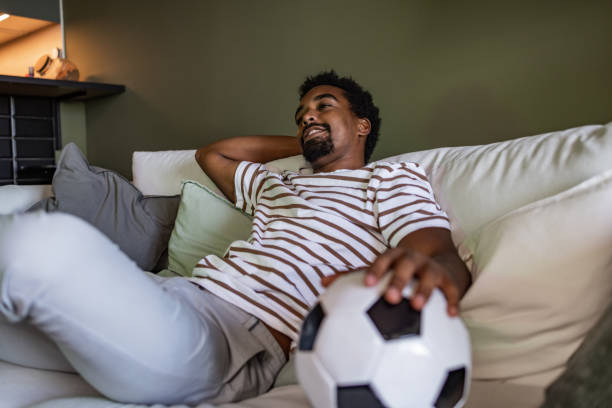 istock Soccer fan sitting on the couch and watching a game 1430105037