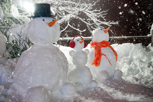 Snowmen Family in the Winter Night near the Street Lamp