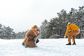 Young family having fun in winter snowy forest