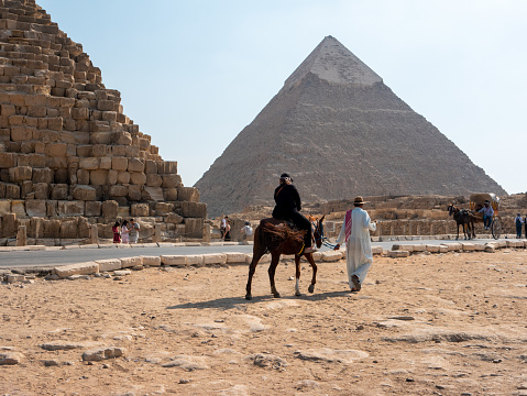 Giza, Cairo, Egypt - September 30, 2021: Pyramids of Giza, a complex of ancient monuments on the Giza plateau. Egyptians ride tourists on horses and carts near the pyramid.
