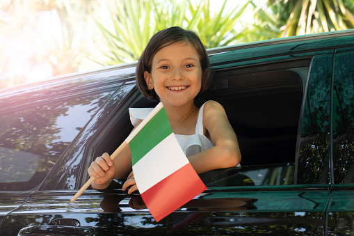 Girl holding Italian Flag in the car.