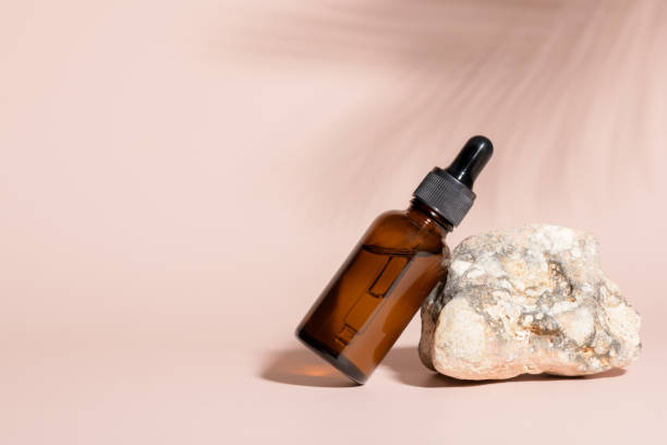 istock Amber glass bottle for serum on stone with palm leaf shadow on beige 1430112761