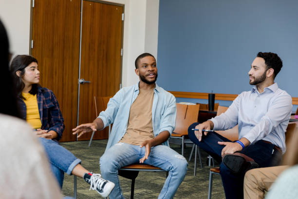 istock Young adult male gestures while talking to the small group 1430112796
