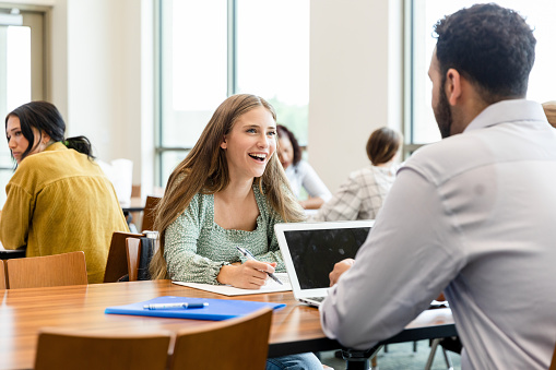 The writing lab professor meets with the young adult female student to help give her some advice regarding her essay.