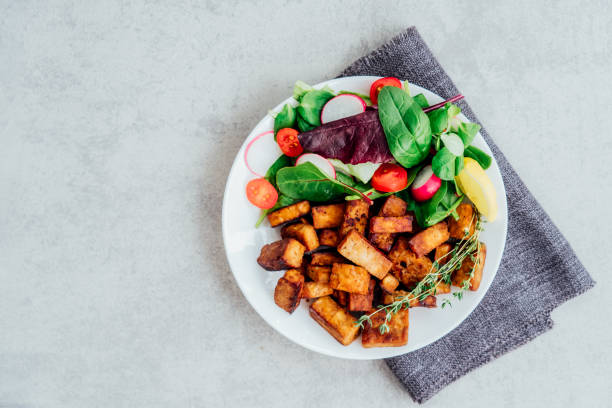 istock Top view healthy salad with cherry tomato, beetroot straws, spinash and lettuce leaves and portion of roasted tempeh, made of fermented soy bean on plate. Plant based protein. Healthy eating. Go vegan 1430115227