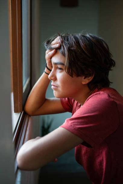 istock sad, worried pre adolescent boy looking out the window 1430126762