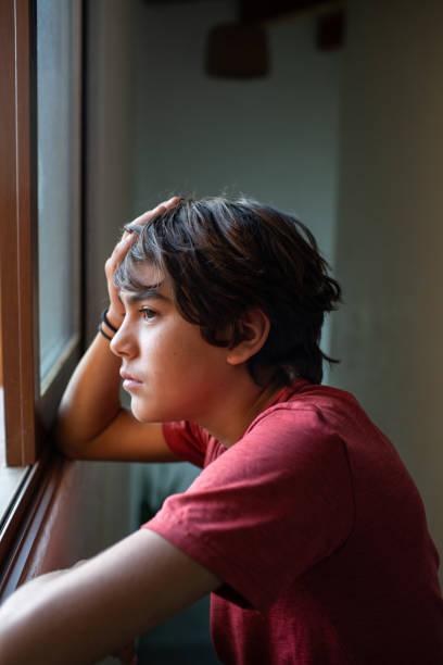 istock sad, worried pre adolescent boy looking out the window 1430126765