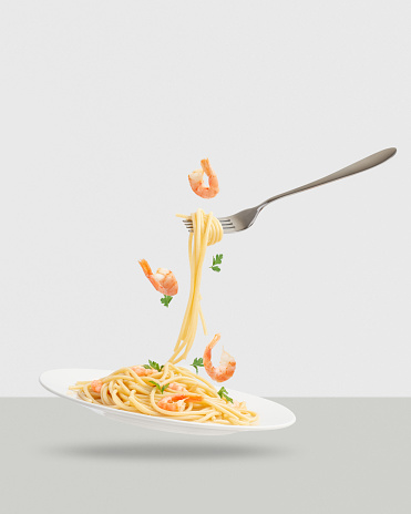 Pasta with levitating ingredients. Pasta with shrimps and parsley. Pasta on a fork