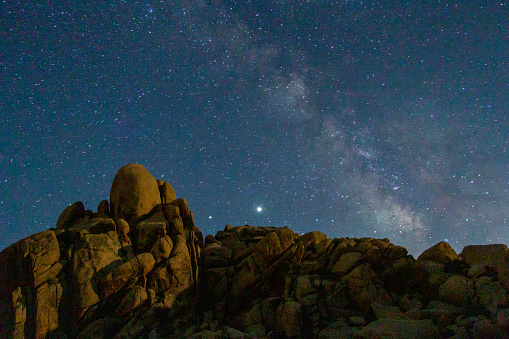 Milky Way seen over boulders taken at night in Joshua Tree National Park while camping.