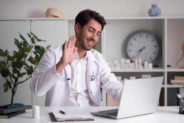The doctor, who finished his online interview, waved goodbye to his patient stock photo