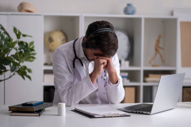istock handsome young male doctor in wireless headphones talking, using laptop 1430132432