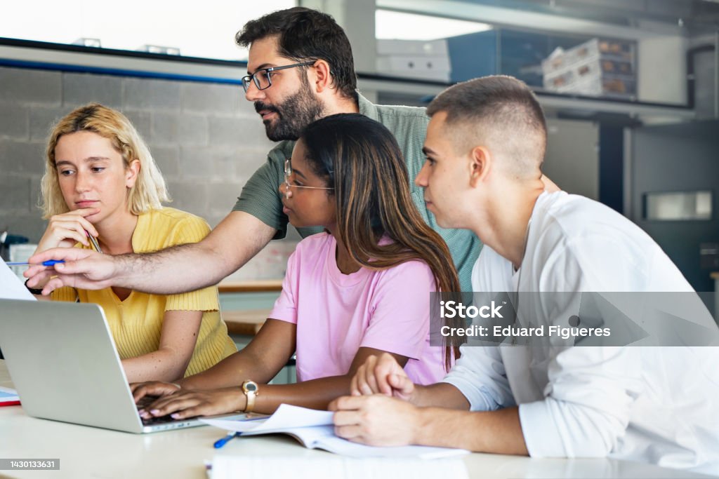 Young teacher helping teenager students at College, learning technology and science in preparatory course for university Teacher Stock Photo