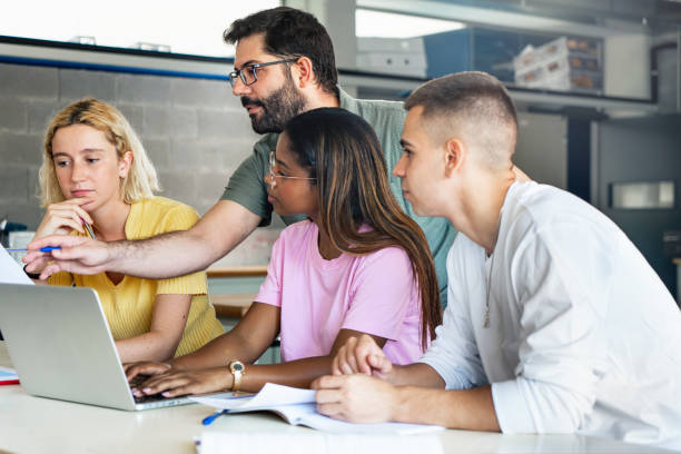 młody nauczyciel pomagający nastoletnim studentom w college'u, technologii uczenia się i nauk ścisłych w kursie przygotowawczym do uniwersytetu - teacher computer high school student classroom zdjęcia i obrazy z banku zdjęć