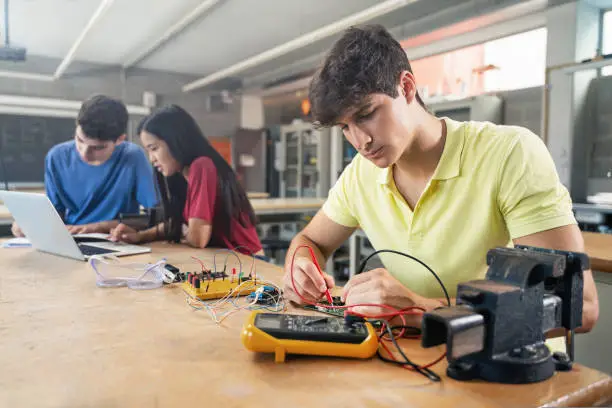 College Student working on electronics circuit in the science technology workshop - Digital Innovation in Education