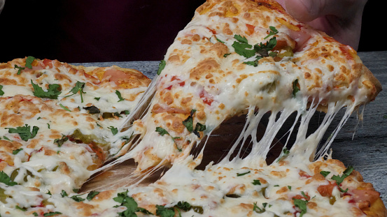 Meal time at pizzeria, man taking a slice of the pizza shot with very thin depth of field. Frame. Hand cut slice of pizza and take it, close up, macro shot. Pizza and slice of pizza in hand on the table.