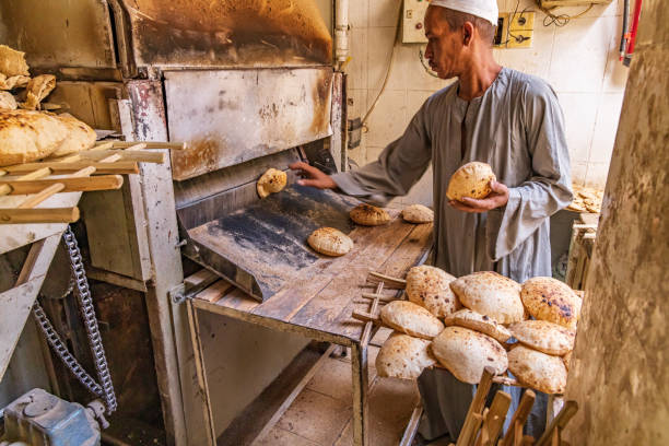 Thebes, Luxor, Egypt. February 24, 2022. Baker making pita bread with an automated oven.