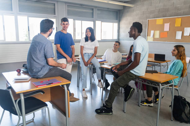 élèves et jeunes enseignants ayant une conversation en classe - highschool student photos et images de collection