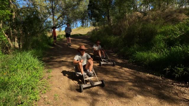Friends racing go carts on driveway in outback Australia