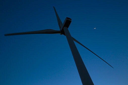 Wind turbine silhouette against deep blue evening sky