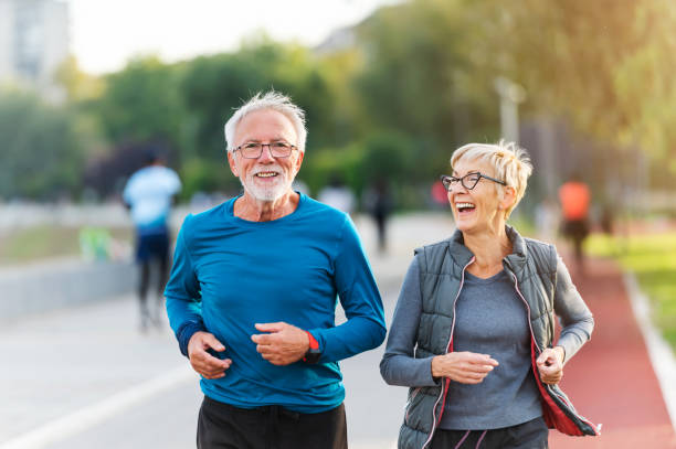 joyeux couple de personnes âgées actives faisant du jogging ensemble à l’extérieur le long de la rivière. activités saines pour les personnes âgées. - résistance photos et images de collection