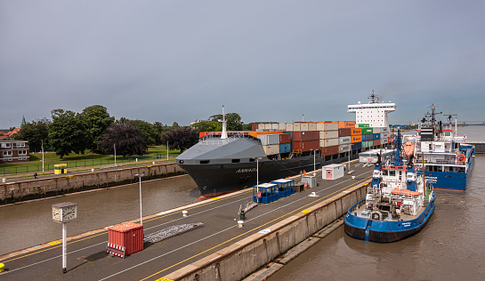 Brunsbuttel, Germany - July 12, 2022: Kiel Kanal lock, North Sea side. 3 ships in the locks under thickening gray sky