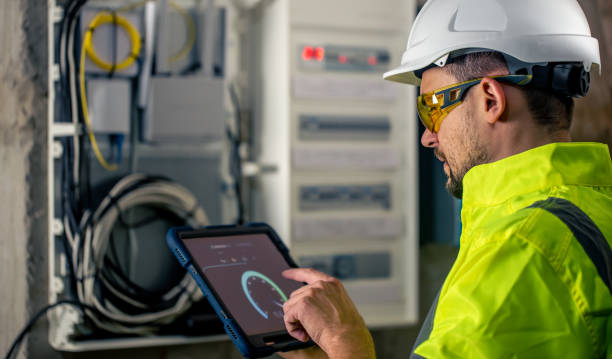 istock Man an electrical technician working in a switchboard with fuses, uses a tablet. 1430150470