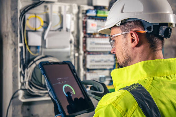 istock Man, an electrical technician working in a switchboard with fuses, uses a tablet. 1430150486