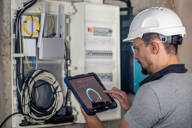 istock Man, an electrical technician working in a switchboard with fuses, uses a tablet. 1430150661