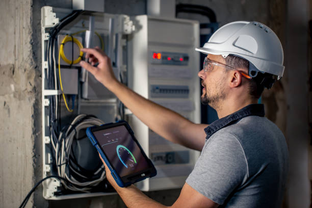 istock Man, an electrical technician working in a switchboard with fuses, uses a tablet. 1430150675