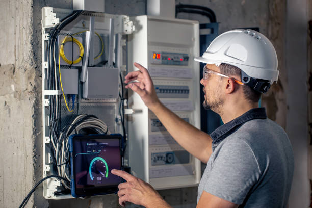 istock Man, an electrical technician working in a switchboard with fuses, uses a tablet. 1430150676