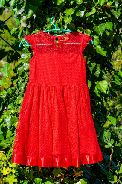 child dress hanging on green fabric greenery background.