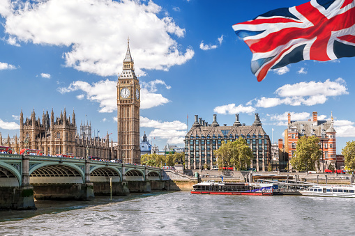 Big Ben con puente sobre el Támesis y bandera de Inglaterra contra cielo azul en Londres, Inglaterra, Reino Unido photo