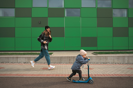 other and son having fun. Happy family mother teaches child son to ride a scooter. Support childhood parenthood idea. Happy family concept.