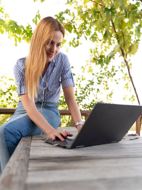 istock Young woman sitting in public park and using laptop 1430154533