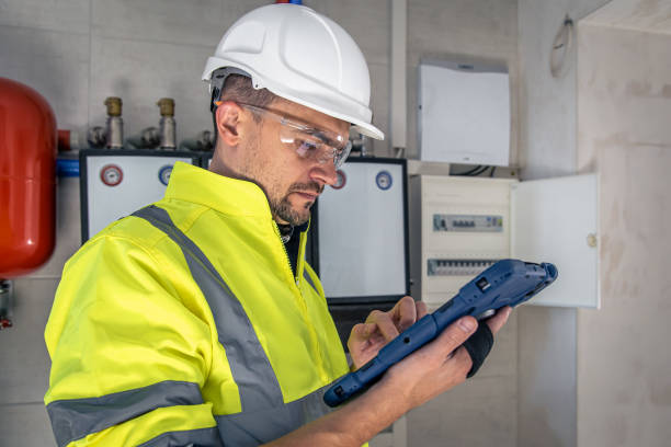 istock Man, an electrical technician working in a switchboard with fuses, uses a tablet. 1430157798