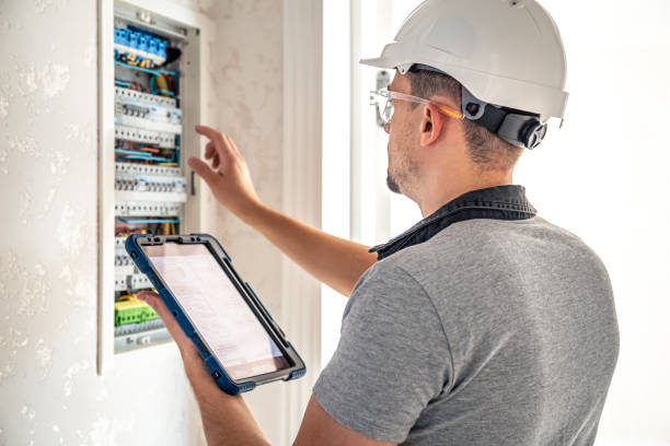 istock Man, an electrical technician working in a switchboard with fuses, uses a tablet. 1430157804