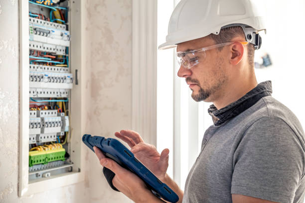 istock Man, an electrical technician working in a switchboard with fuses, uses a tablet. 1430157807