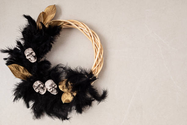 istock Handmade boho halloween wreath background with copy space. Wreath made of black feathers, skulls and golden leaves 1430163238