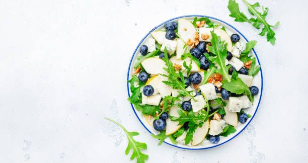 istock Delicious arugula salad with pears, blueberries, roquefort cheese and walnuts. Black kitchen table background, top view 1430165148