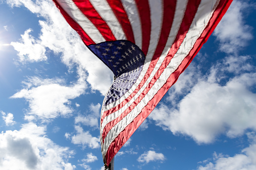 Close-up of American flag waving against blue sky.