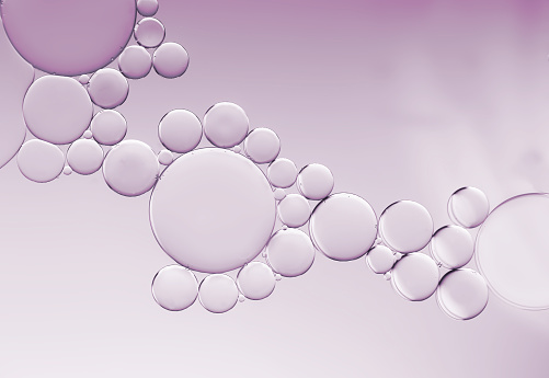 Abstract image created by an interesting  mixture of different sized oil droplets highlighted by pale lavender  lighting effects.
