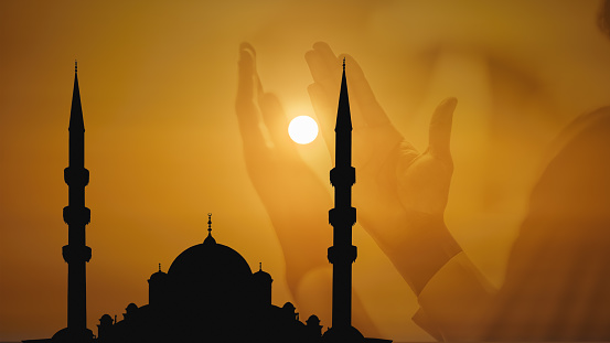 islamic background of silhouette islamic mosque with background of sunrise sky overlay with muslim hands worship and praying to allah god. islamic background to celebrate holy ramadan