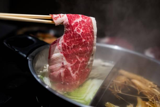 istock Hand using chopsticks pick premium raw beef sliced beef over the hot pot soup for Shabu Shabu 1430189538