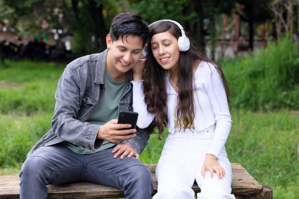 istock Latino couple using cell phone in park 1430193067