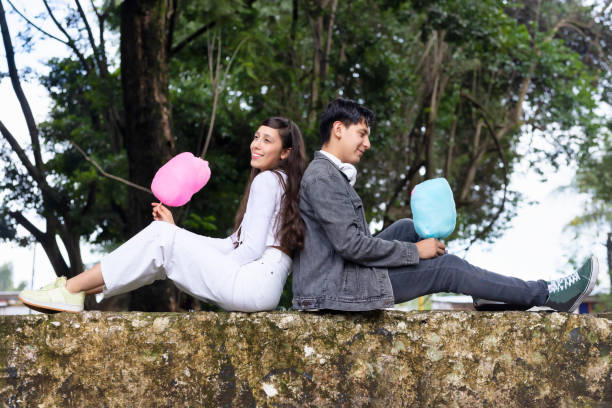 Couple sitting on their backs enjoying a cotton candy.