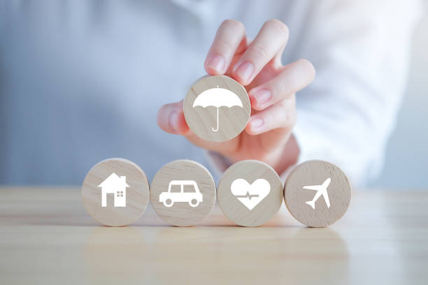 istock Insurance concept. Protection against a possible eventuality. Hand holding umbrella icon for security symbol and House, Car, Health care and travel icon on wooden circle for assurance life concept. 1430207174